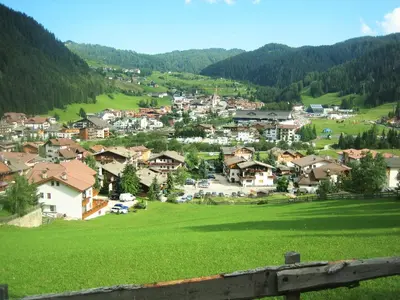 a village on a hill with a green field at La Cianò in Corvara in Badia