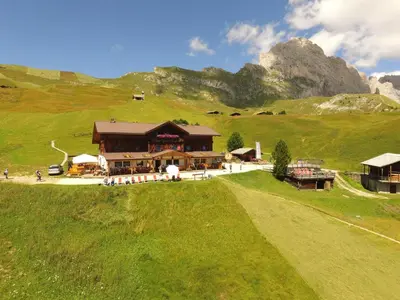 a building in a field with a mountain in the background at Rifugio Fermeda Hutte in Santa Cristina in Val Gardena
