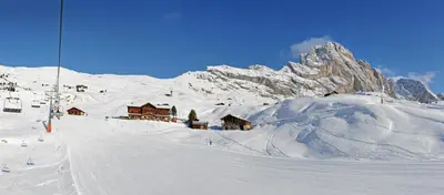a house on a green hill with mountains in the background at Rifugio Fermeda Hutte in Santa Cristina in Val Gardena