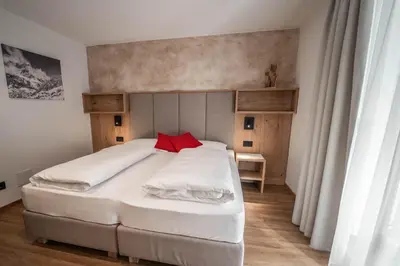 a small bedroom with a bed and a table at Garnì Piz da L'Ander in Corvara in Badia