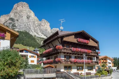 a building with flowers on the side of a street at Garnì Piz da L'Ander in Corvara in Badia
