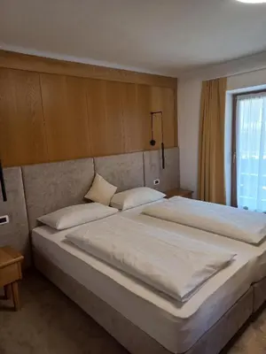 a bedroom with two beds and a red curtain at Garnì Piz da L'Ander in Corvara in Badia