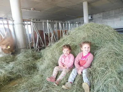 two little girls sitting in a pile of hay at Leitnerhof in Terento