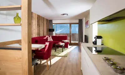 a living room with a red couch and a table at Familyparadies GAMPLALM in Lana