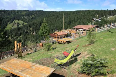 a house on a hill with chairs and a table at Familyparadies GAMPLALM in Lana