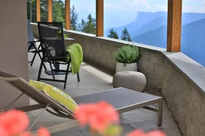 a balcony with chairs and a table and a view of mountains at Familyparadies GAMPLALM in Lana