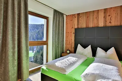 a bedroom with a green bed with a large window at Familyparadies GAMPLALM in Lana
