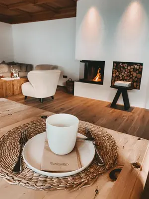 a table with a plate and a cup and a fireplace at Mountain Chalet Pra Ronch in Selva di Val Gardena