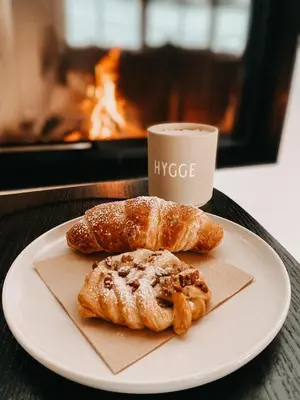 two pastries on a plate next to a cup of coffee at Mountain Chalet Pra Ronch in Selva di Val Gardena