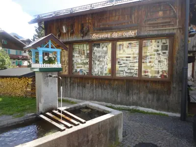 a building with a fountain in front of a store at Sella Ronda Apartment in Campitello di Fassa