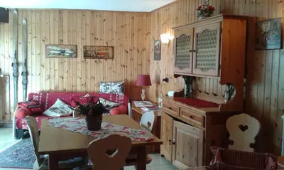 a living room with a red couch and a table at Sella Ronda Apartment in Campitello di Fassa