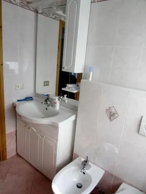 a kitchen with white cabinets and a sink and a stove at Gal28 in Predazzo