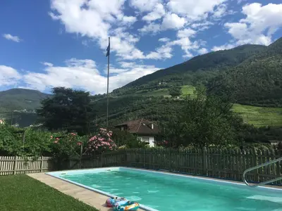 a swimming pool with a fence and mountains in the background at Weingut Zundlhof in Bolzano