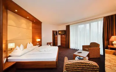 a hotel room with a bed and a chair at Hotel Anatol in Merano