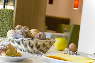 a basket of donuts and an apple on a table at Hotel Anatol in Merano