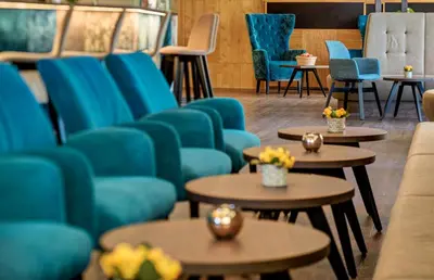 a waiting room with blue chairs and tables at Hotel Anatol in Merano