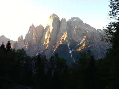 a tall mountain with the sun shining on it at Telemark Mountain Rooms in Agordo