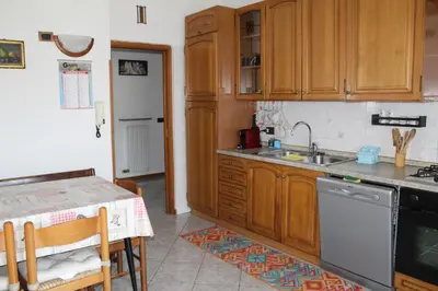 a kitchen with wooden cabinets and a sink and a table at Appartamento Widmann in Coredo