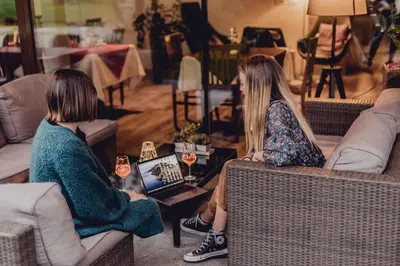two women sitting on couches in a living room at Hotel Raffl in Bolzano