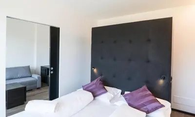 a bedroom with a large bed with purple pillows at Hotel Raffl in Bolzano