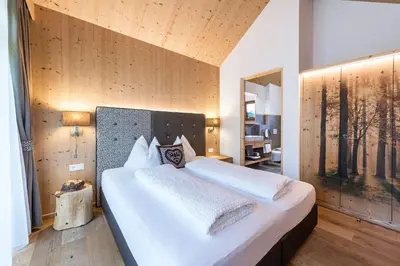 a bedroom with a large bed and a large window at Niederthalerhof Chalets in Bressanone