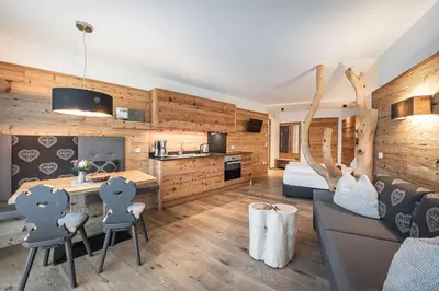 a room with a couch and a table and a kitchen at Niederthalerhof Chalets in Bressanone