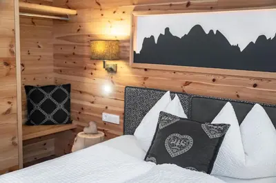 a bedroom with a large white bed with a window at Niederthalerhof Chalets in Bressanone