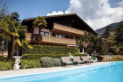a house with a swimming pool in front of a house at Hotel Schönbrunn in Merano