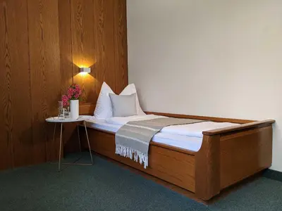 a bed in a room with a table with flowers on it at Hotel Schönbrunn in Merano