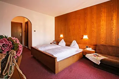 a bedroom with a bed and a couch at Hotel Schönbrunn in Merano