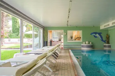 a pool with white chairs and a swimming pool at Glanzhof Hotel & Apartments in Marlengo