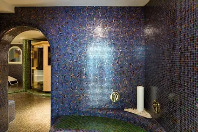 a bathroom with a blue tiled wall with a tub at Glanzhof Hotel & Apartments in Marlengo