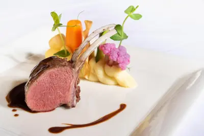 a piece of meat on a white plate with vegetables at Glanzhof Hotel & Apartments in Marlengo