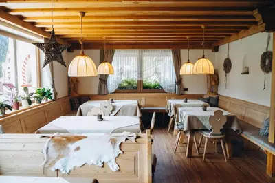 a restaurant with white tables and chandeliers at Garni Cir in Santa Cristina in Val Gardena