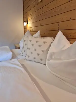 a bed with white sheets and pillows at Garni Cir in Santa Cristina in Val Gardena