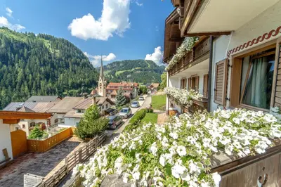 a woman standing outside of a building with flowers at Garni Cir in Santa Cristina in Val Gardena
