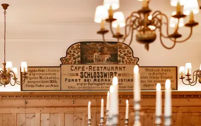 a sign on top of a table with candles at Schlosswirt Forst in Lagundo