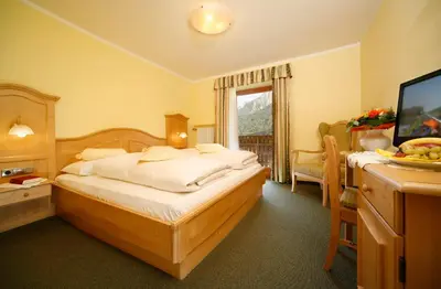 a hotel room with a bed and a television at Hotel Kranebitt in Val di Vizze