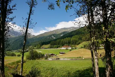 a valley with a farm and mountains in the background at Hotel Kranebitt in Val di Vizze