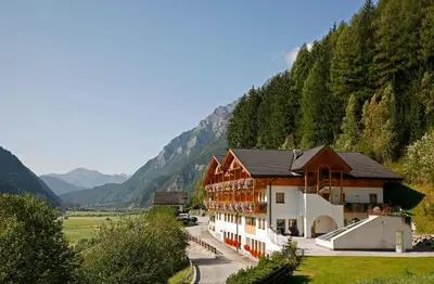 a hotel in a valley with mountains in the background at Hotel Kranebitt in Val di Vizze