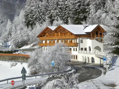 a large building in the snow with snow covered trees at Hotel Kranebitt in Val di Vizze