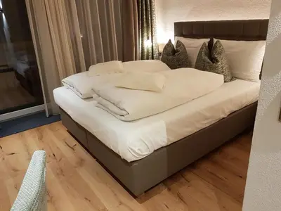 a large bed with white sheets and pillows on it at Hotel Kranebitt in Val di Vizze