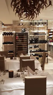 a dining room with white tables and wine racks at Hotel Kranebitt in Val di Vizze
