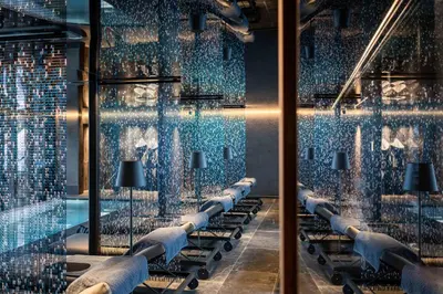 a room with a swimming pool with blue glass walls at Linder Cycling Hotel in Selva di Val Gardena