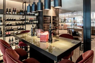 a bar in a wine tasting room with red chairs at Linder Cycling Hotel in Selva di Val Gardena