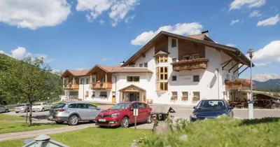 a large building with cars parked in a parking lot at Pension Maria in Antermoia