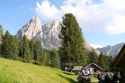 a group of people standing on a hill with mountains in the background at Pension Maria in Antermoia