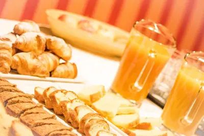 a table with a plate of bread and orange juice at Pension Maria in Antermoia