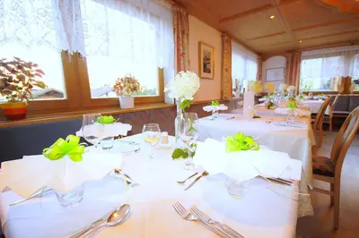 a dining room with white tables with green bows at Pension Maria in Antermoia