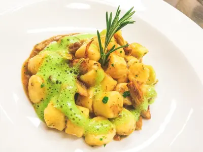 a white plate of food with shrimp with a sauce at Pension Maria in Antermoia